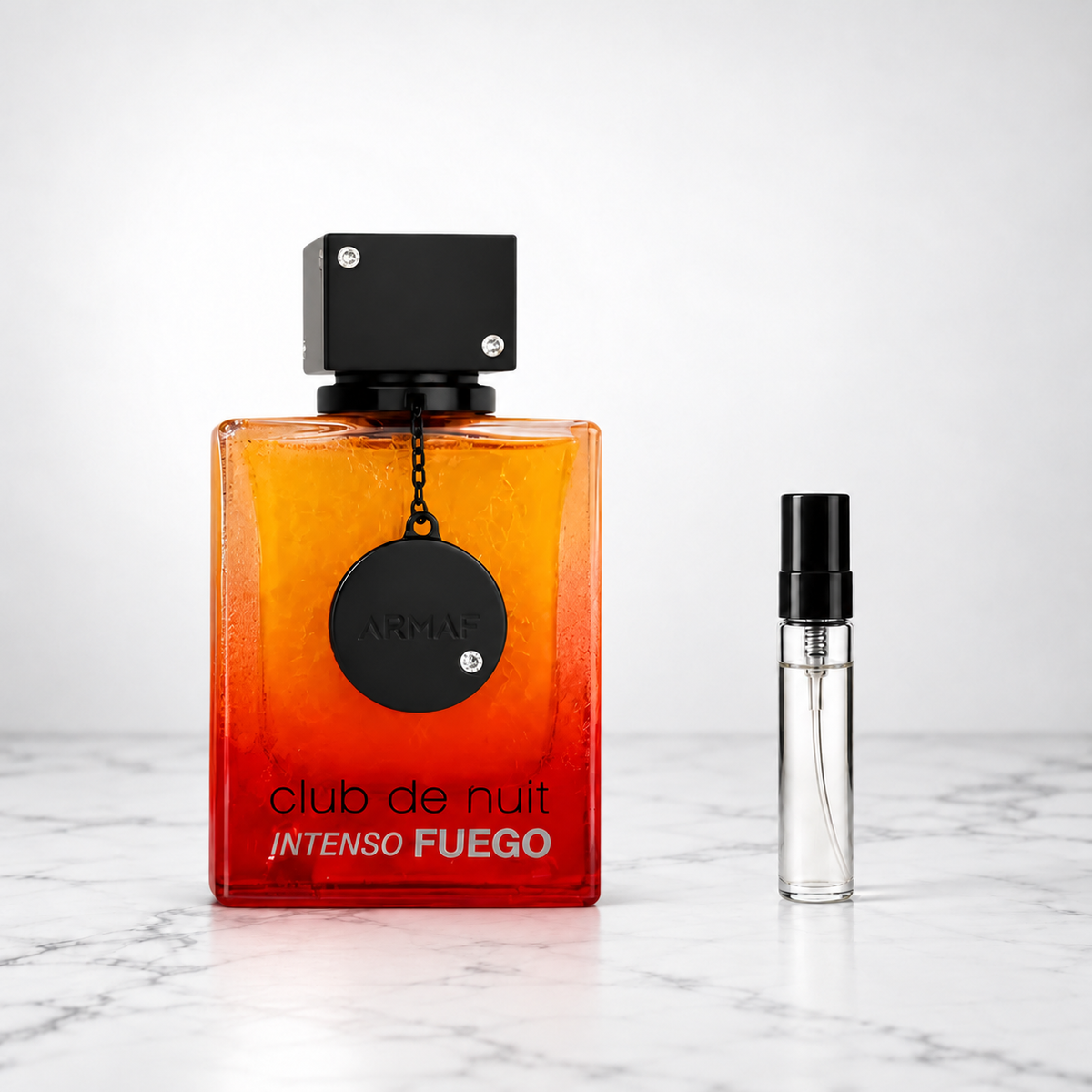 Club de Nuit Intenso Fuego by Armaf perfume bottle beside a sample decant on white marble