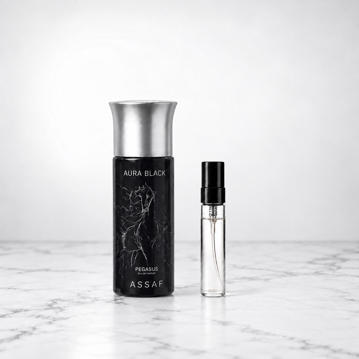 Aura Black by Assaf bottle beside a capped sample decant on white marble