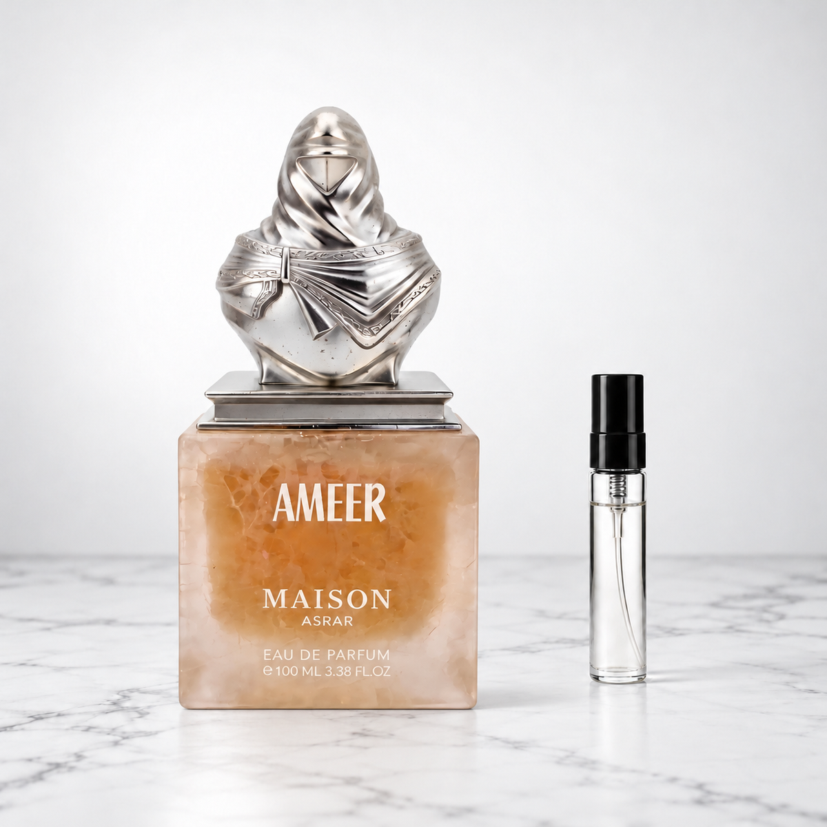 Ameer by Maison Asrar perfume bottle beside a sample decant on white marble