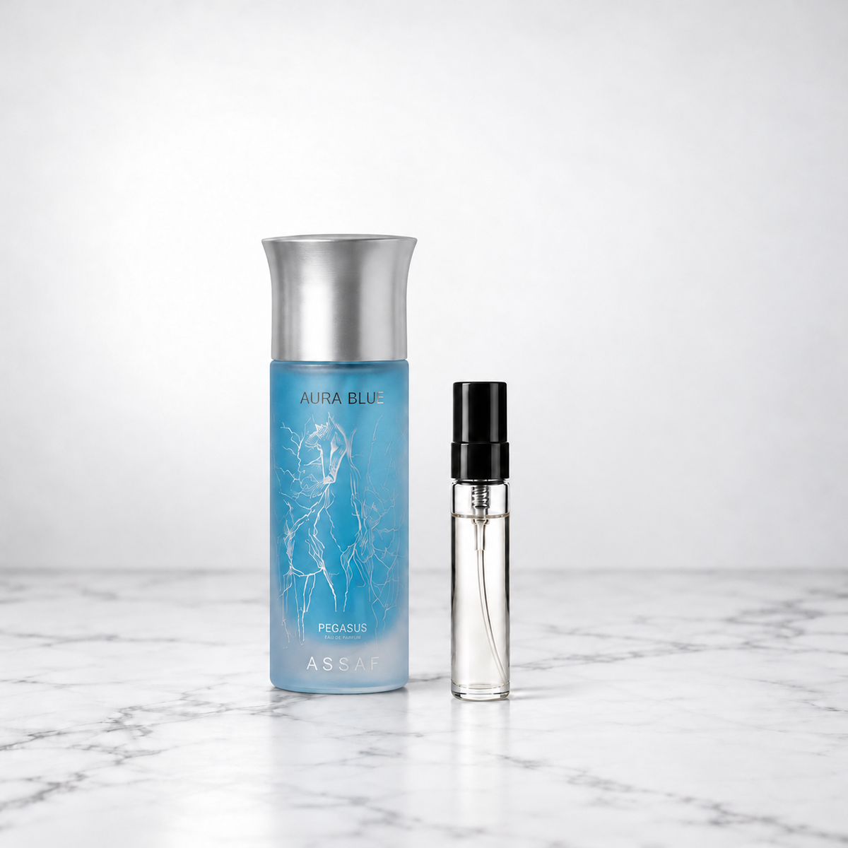 Aura Blue by Assaf bottle beside a capped sample decant on white marble
