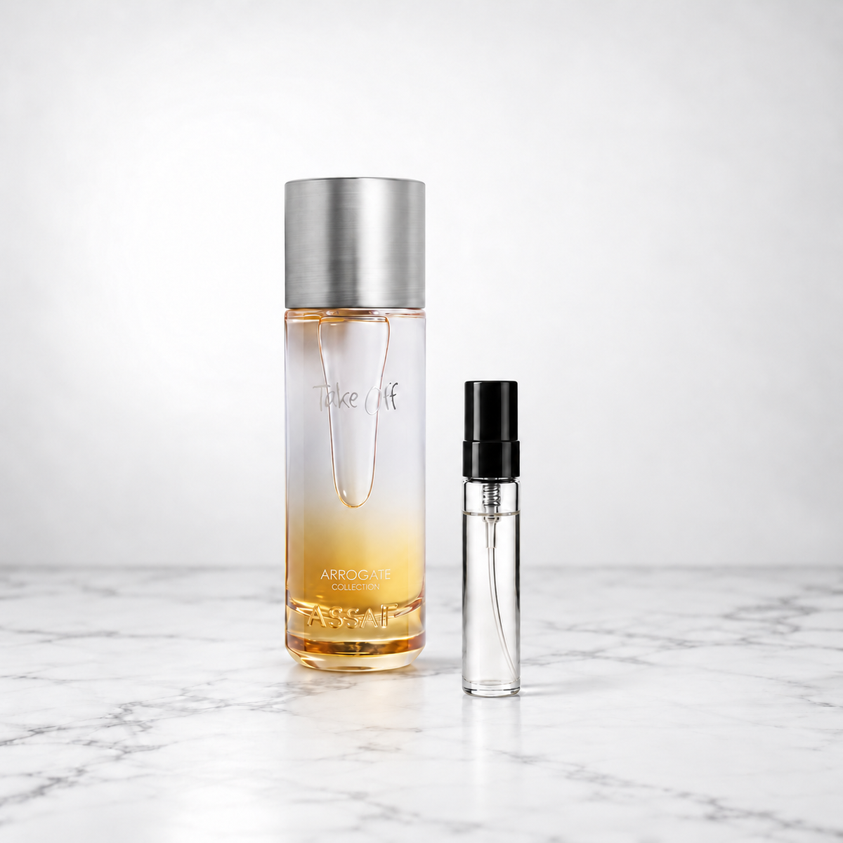 Take Off by Assaf bottle beside a capped sample decant on white marble