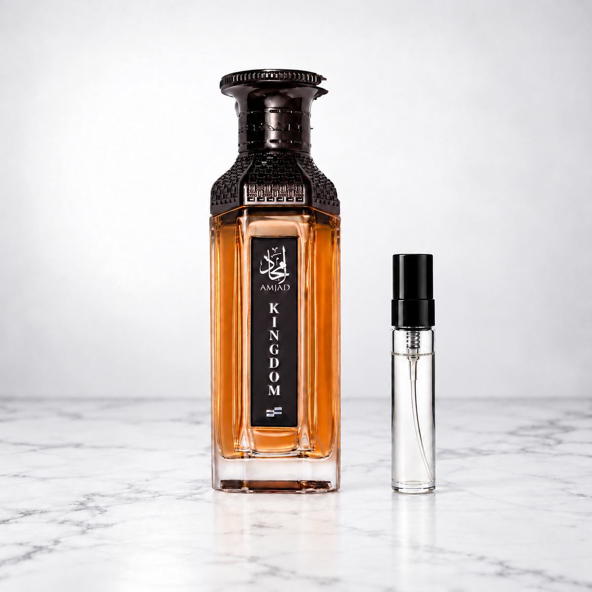 Amjad Kingdom by FAAN perfume bottle beside a capped sample decant on white marble