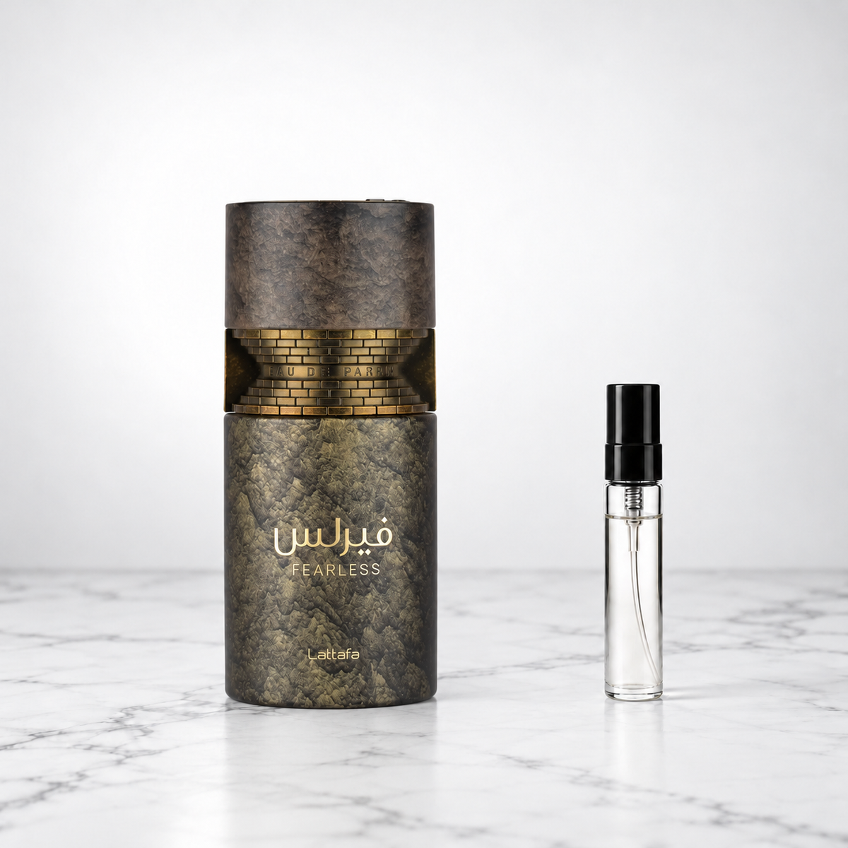 Fearless by Lattafa perfume bottle beside a sample decant on white marble
